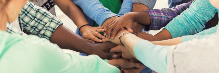 Image of a group of people placing their hands in the centre