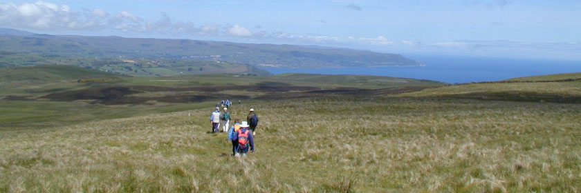 Photograph of people walking across the Glens of Antrim towards the coast