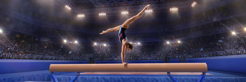 Gymnast on the beam doing a handstand in a stadium