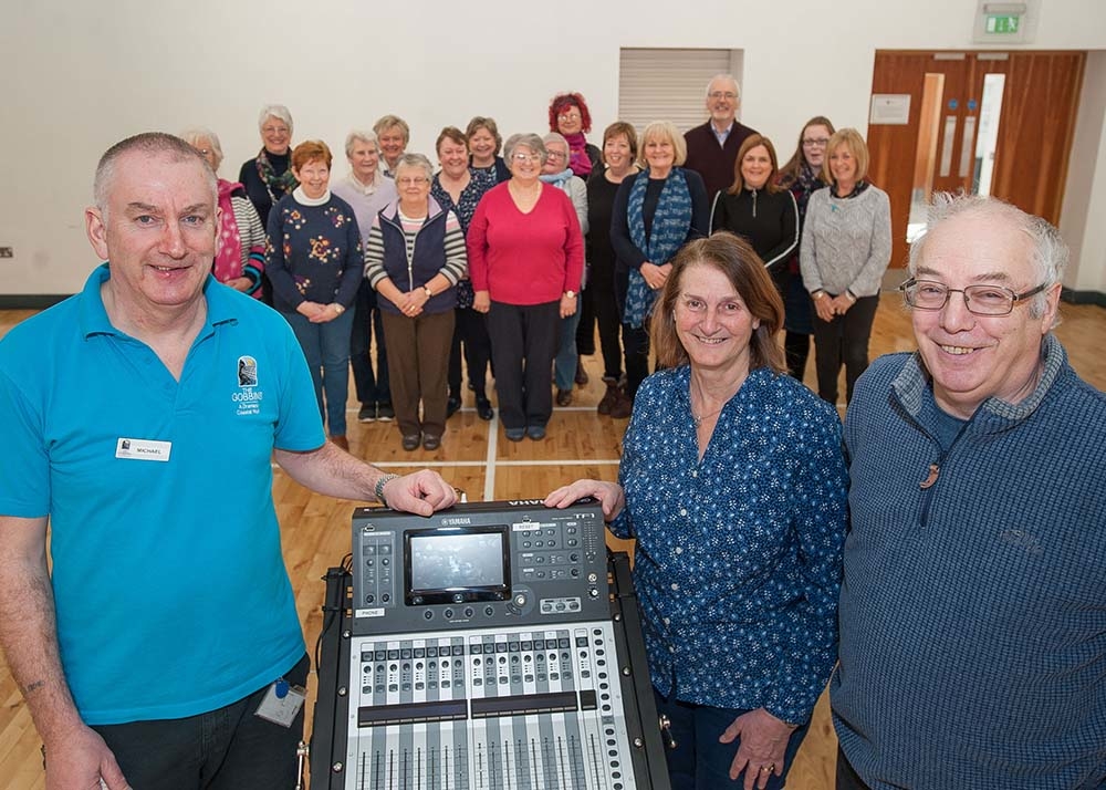 Michael from the Islandmagee Community Centre alongside Hilary and Eric Bailey, with the Island Voices Choir enjoying their new sound system