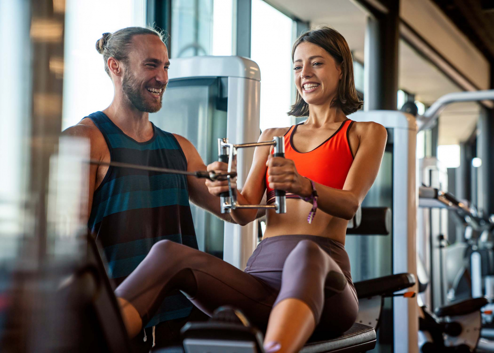 Larne Leisure Centre Update. Image of male personal trainer assisting women on sports equipment.